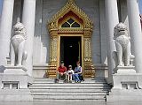 Bangkok 02 04 Wat Benchamabophit Marble Wat Posing at Entrance We decided to get into the same mood, with a team photo. We paused for a few minutes to enjoy the beautiful white marble of the Wat Benchamabophit, with a pair of white marble singhas (mythical lions) framing the stairs.